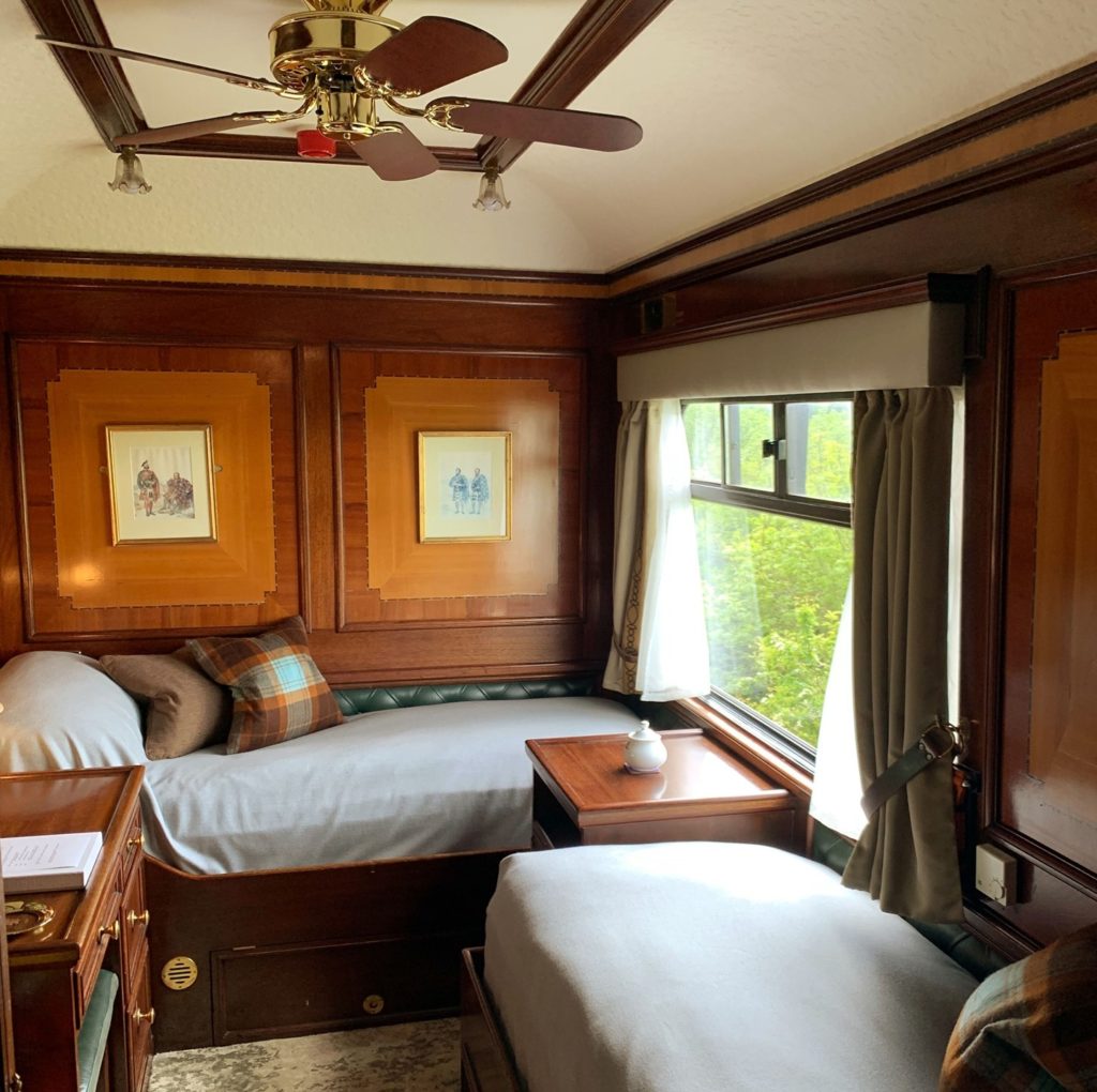 A comfortable sleeper carriage with wooden furnishings and a huge windows is show on this luxury train ride