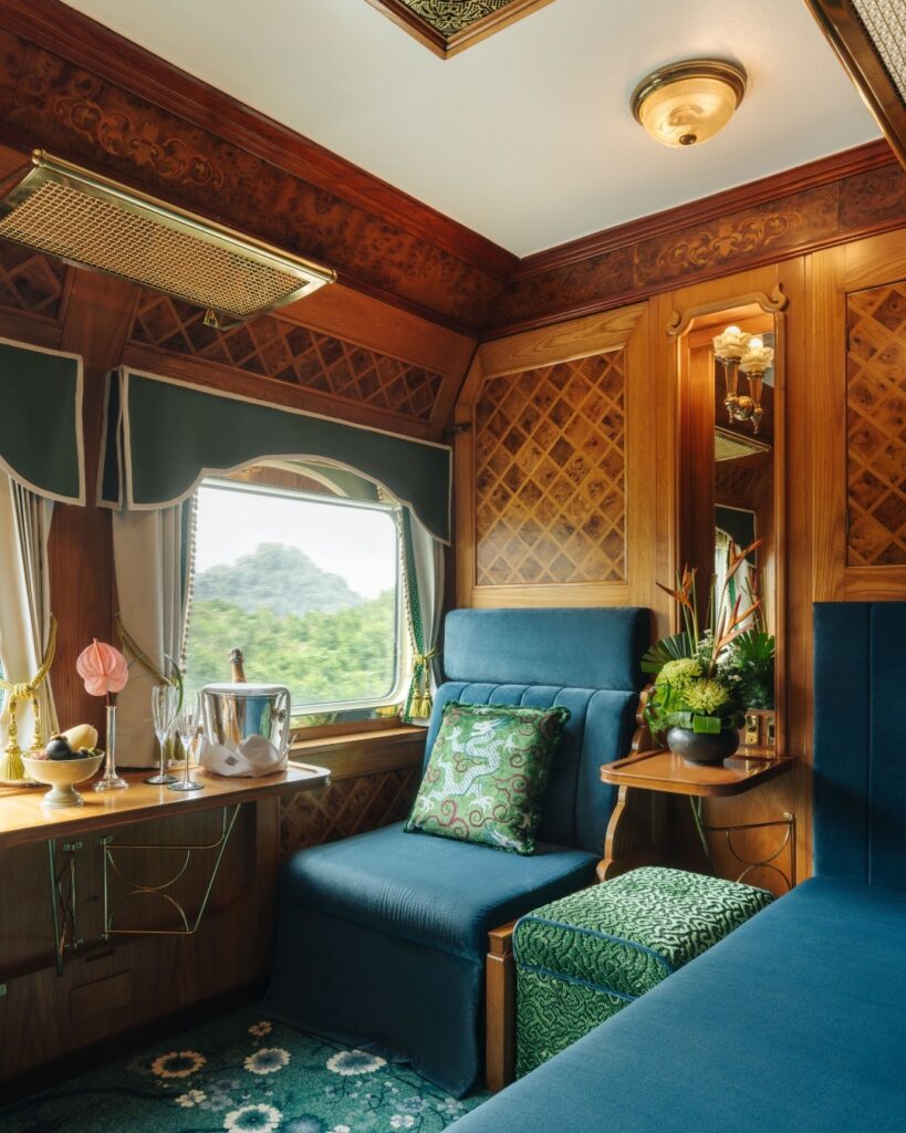 Blue velvet chairs, wooden panelling, and flowers in vases adorn this elegant luxury train carriage