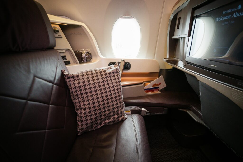 Close up of luxury flight seat, with television and brown leather.