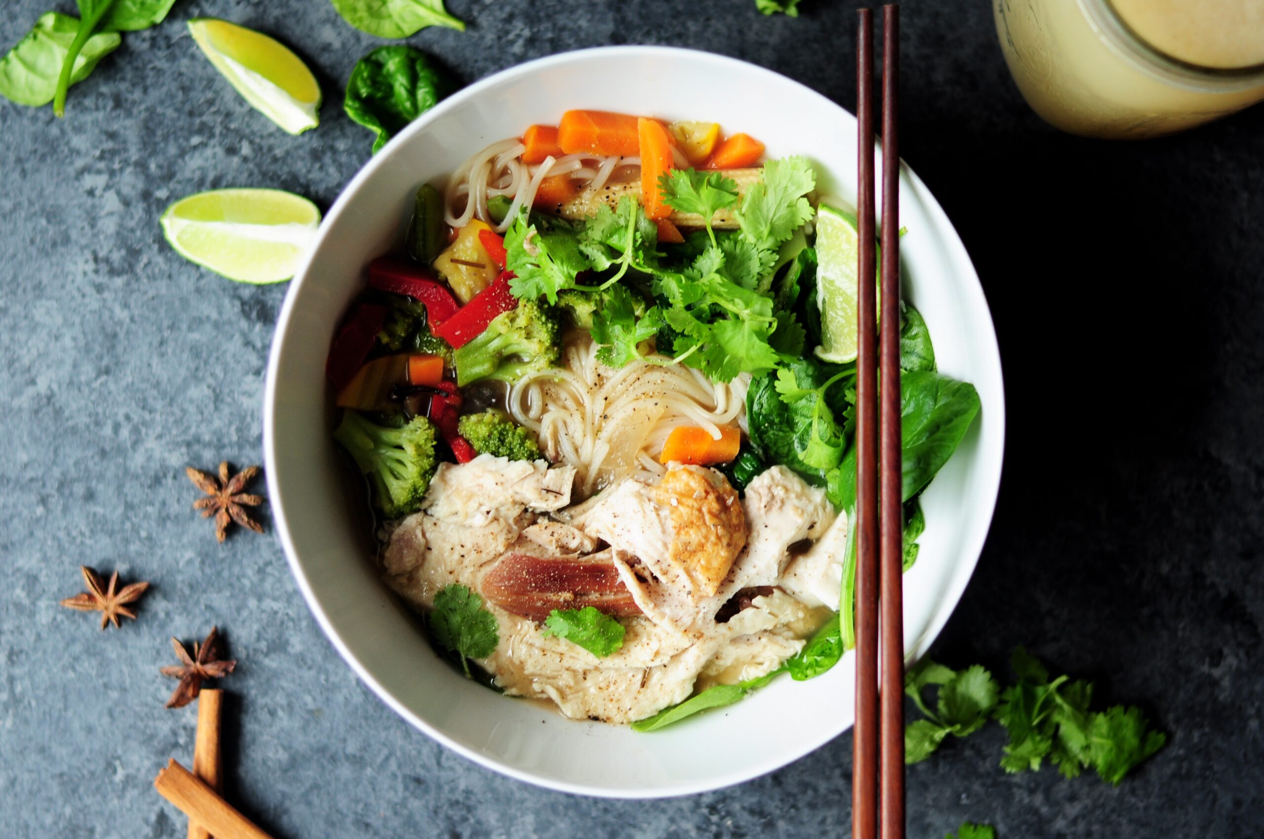 Blown of Vietnamese pho, vibrant colours on the ingredients including chicken, vegetables and herbs