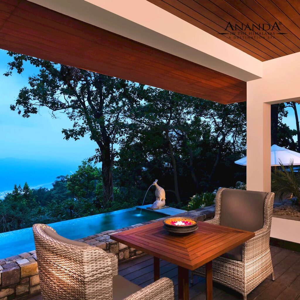 Image of chairs and table on a terrace, overlooking mountain and sea views in the evening light