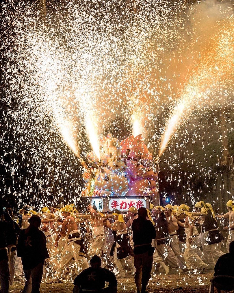 group of people holding a float with sparks flying out spring festival Japan