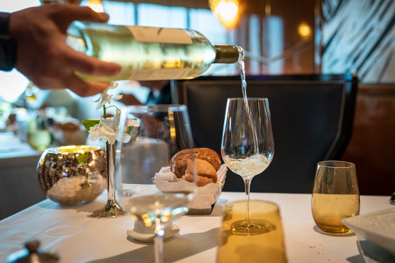 Wine being poured into glass with table set for dining