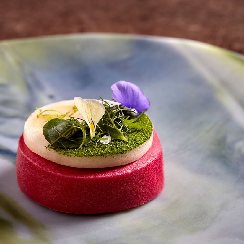 Plate of food with flowers on blue marble plate at COME restaurant 