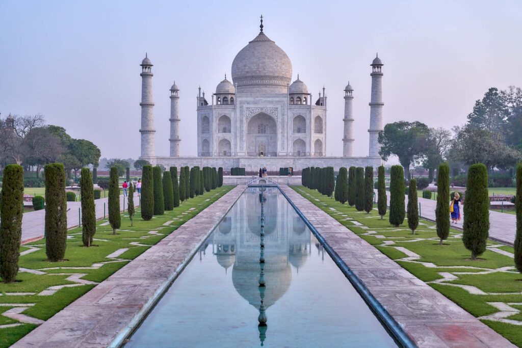 The Taj Mahal against pink clouds with water in foreground 