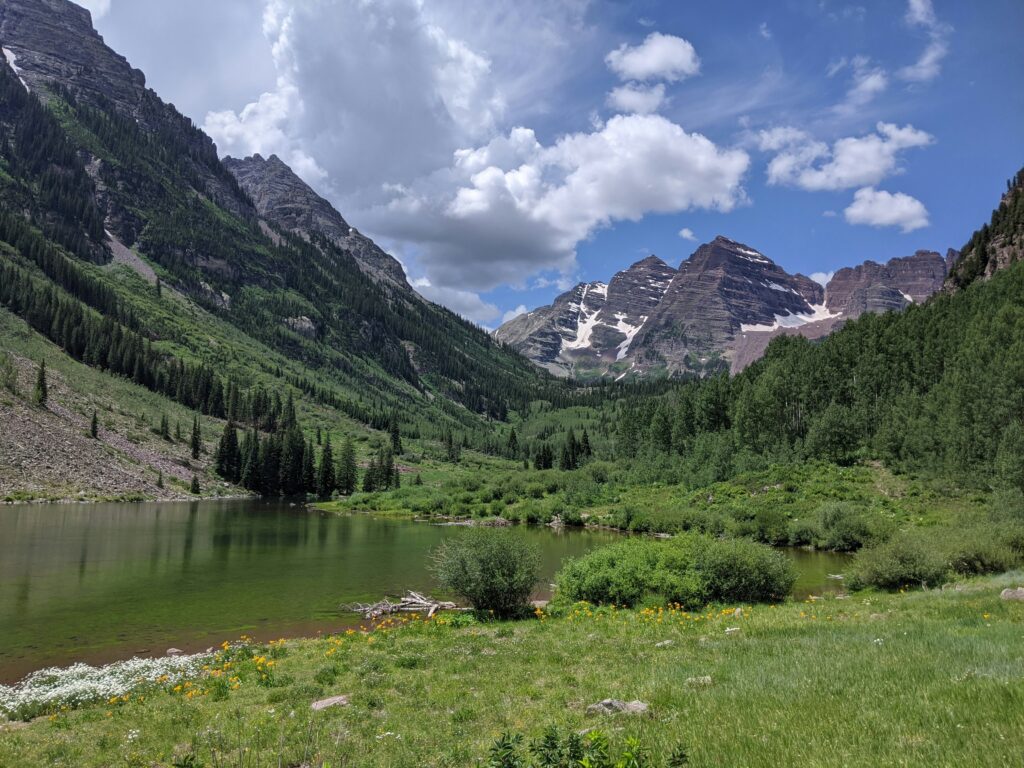 Lush green meadows with a green lake and a backdrop of mountains in Colorado, USA