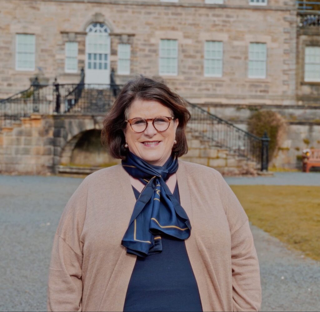 Travel Concierge Shona is pictured smiling in front of a brick building.