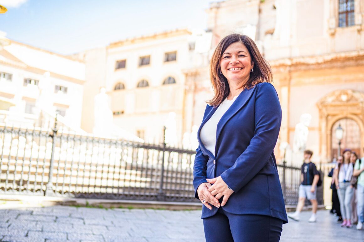 Travel Concierge Elena ia pictured smiling with a blue jacket on a street in Italy