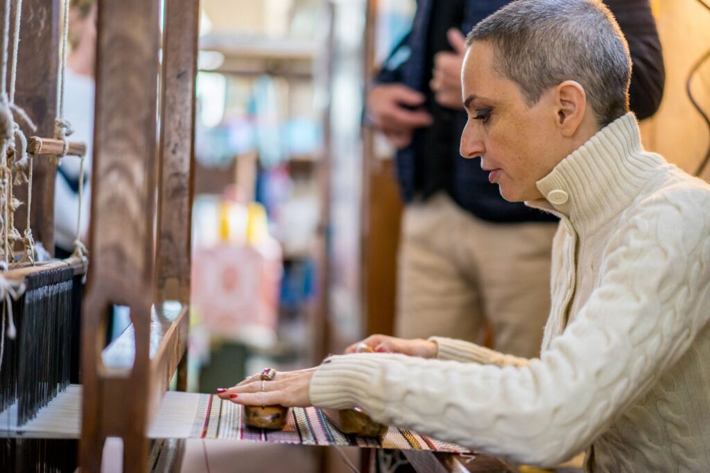 Weaver Marta focusses on threads on an old traditional loomb