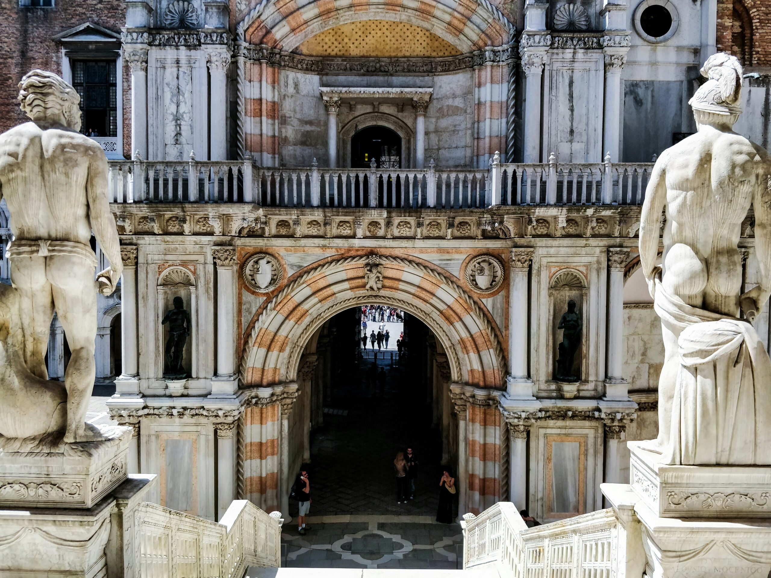 The ornate front of Doges Palace in Italy shows statues, a balcony and intricate stonework