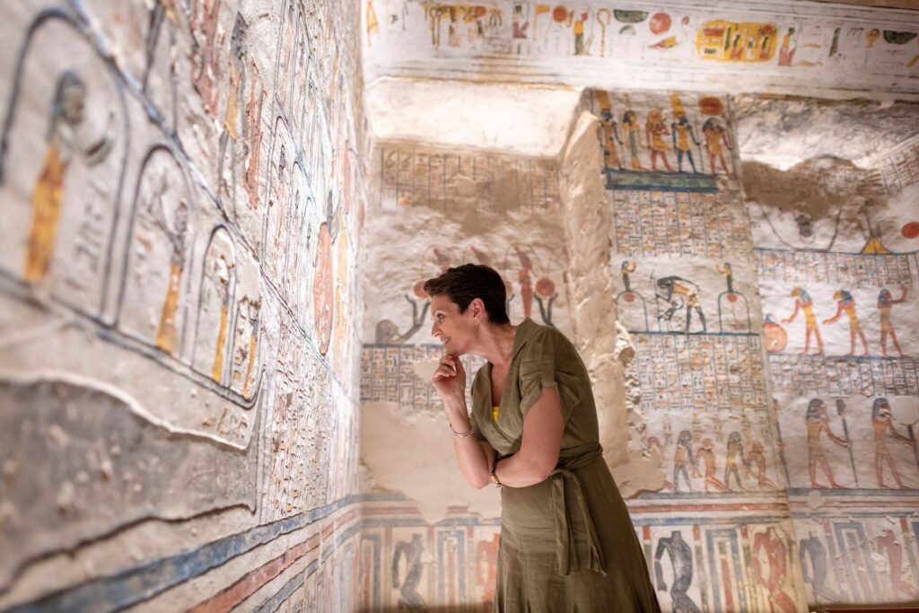 A middle aged lady looks at hieroglyphics, inside in a tomb in Egypt