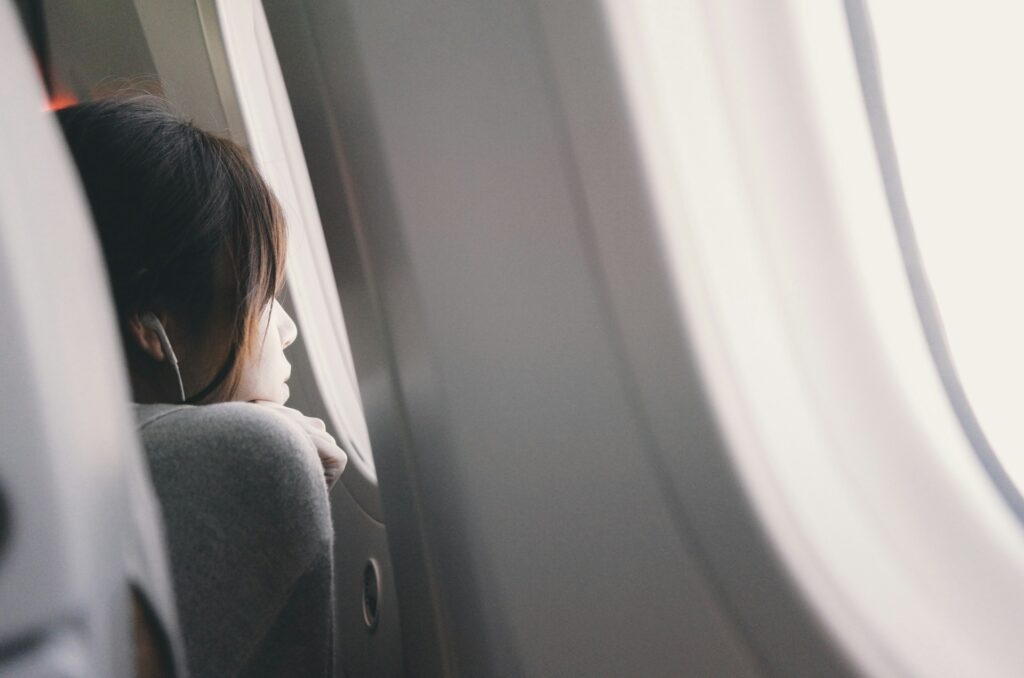 Plane passenger wearing headphones looking out of the window