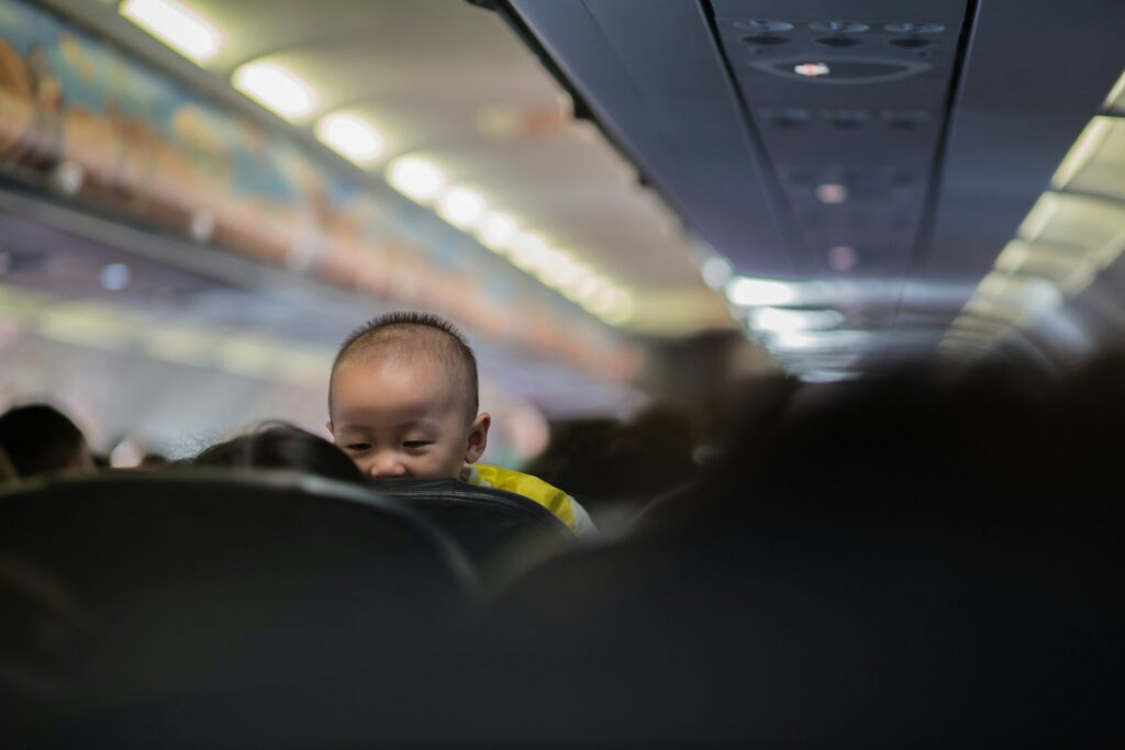 Baby looking over the back of a plane seat