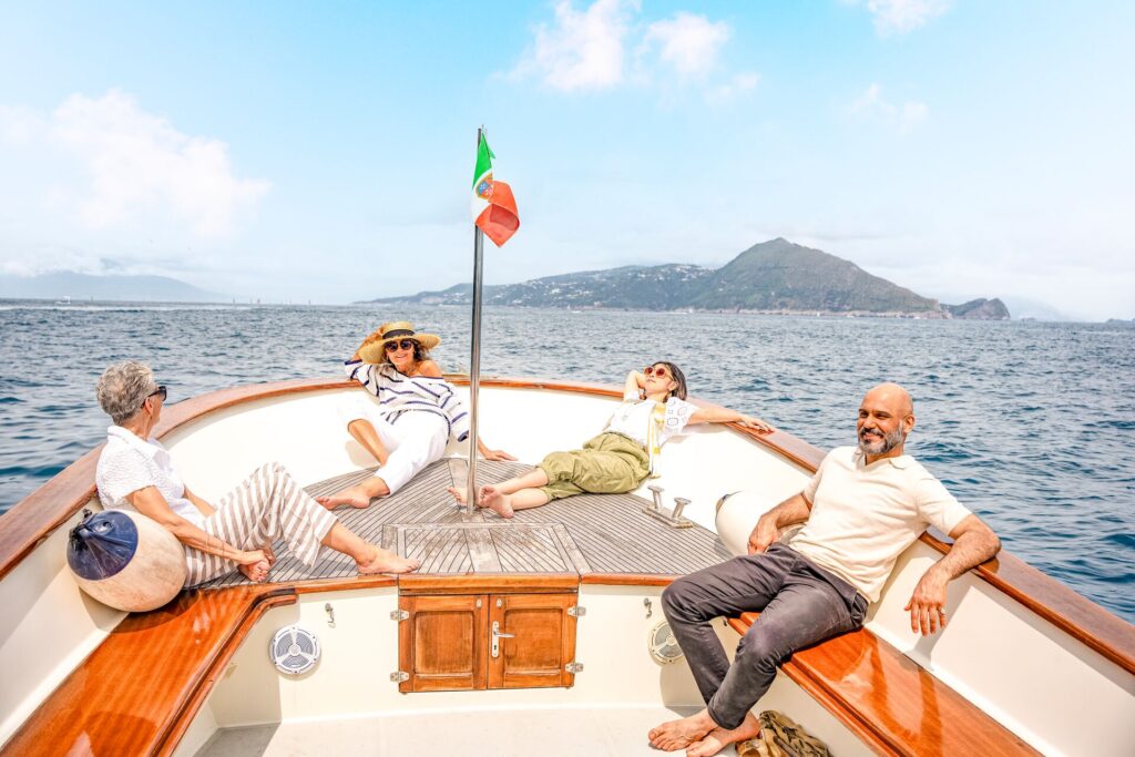 Four guests relax on an open boat, with the sea and a mountain in the background on a Luxury Gold journey in Capri, Italy.