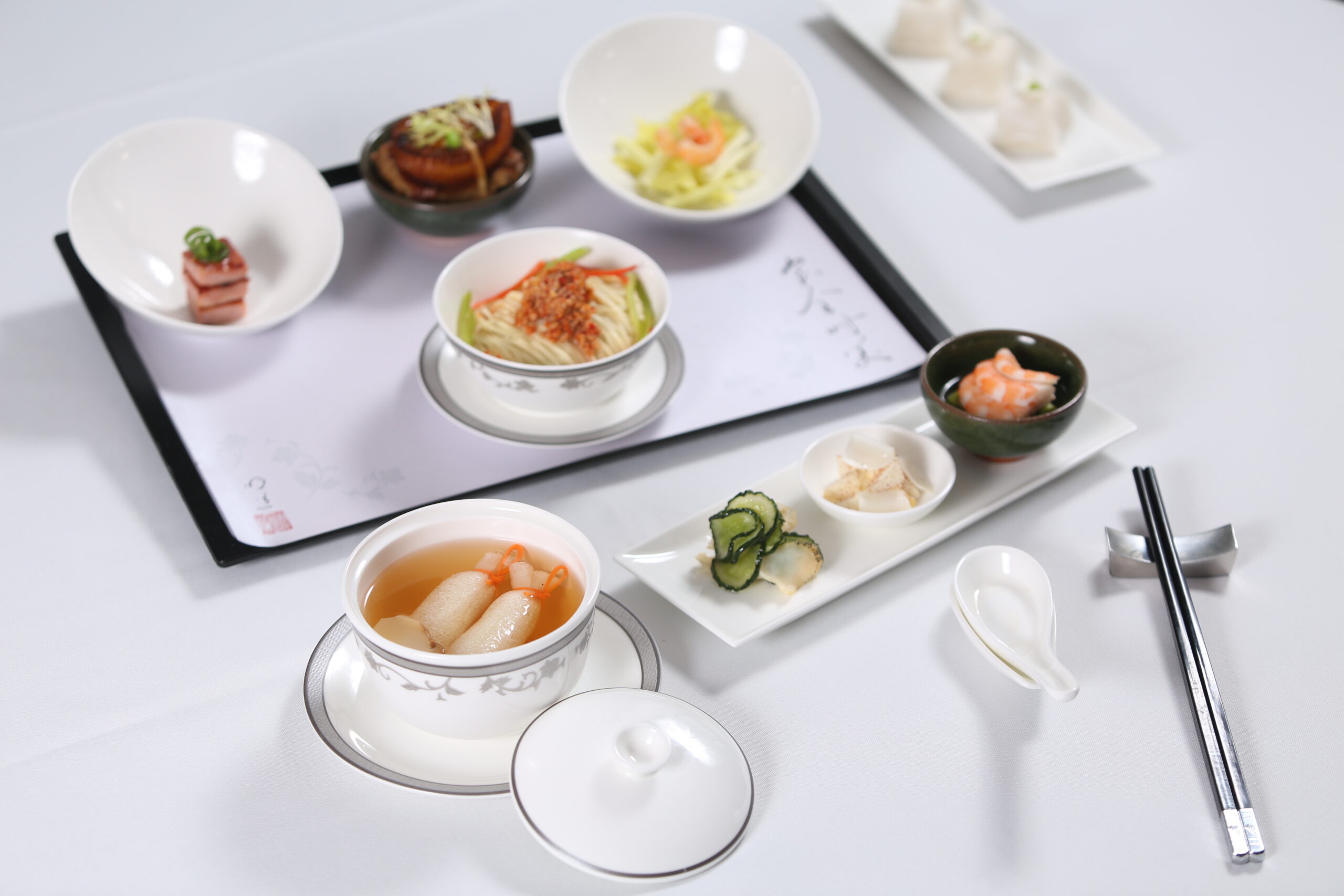 Tray and bowls of Chinese food on a white table cloth