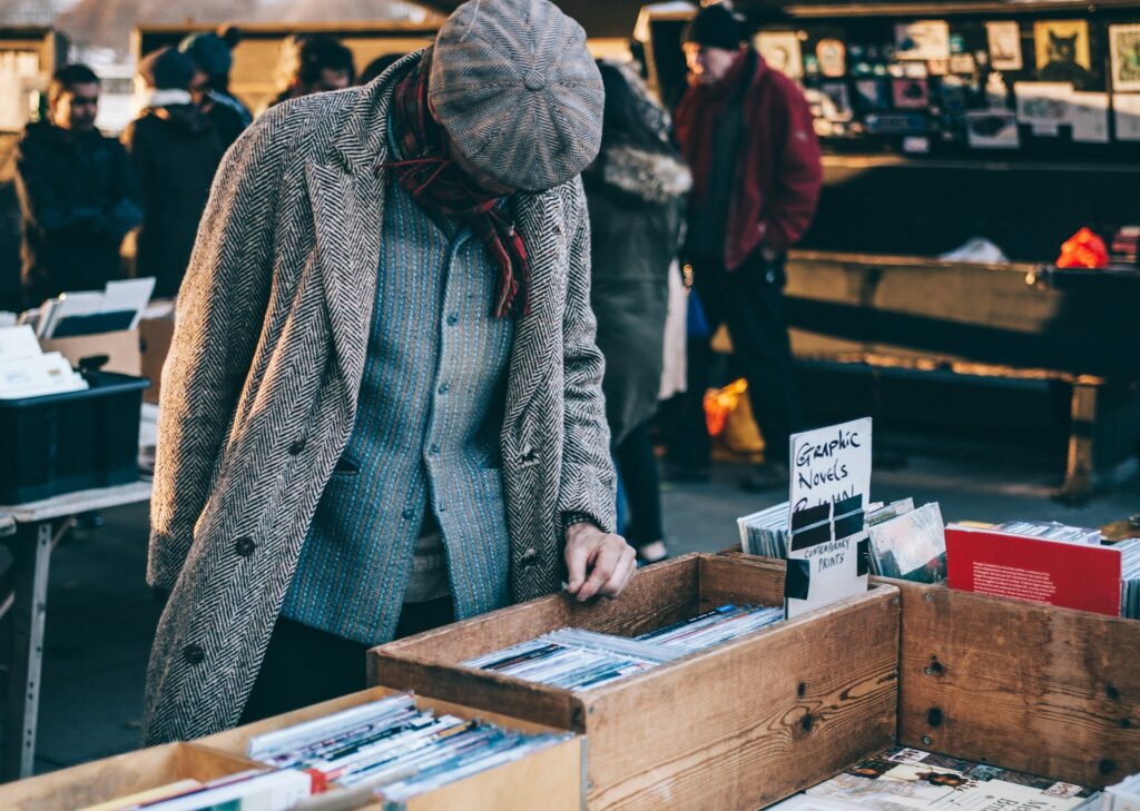 Man browsing an outdoor record market wearing a tweed coat