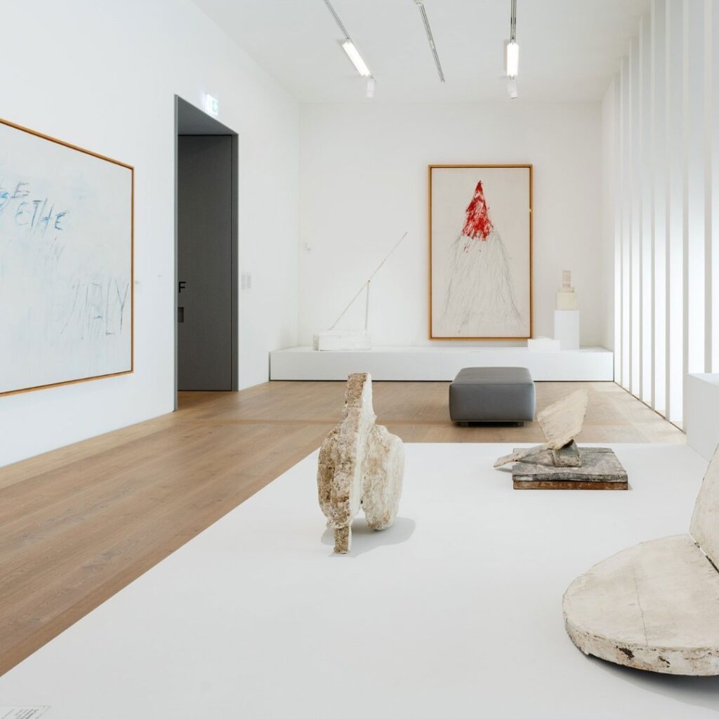 A white museum room with wooden floor shows exhibits.