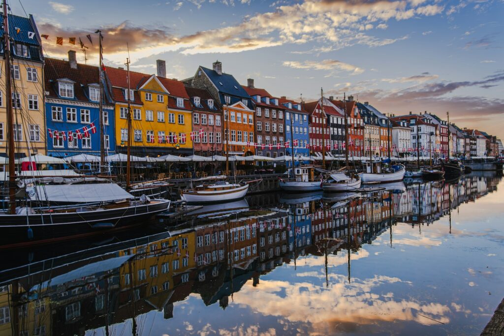 Colourful historic houses line a small habour front with small sailing boats